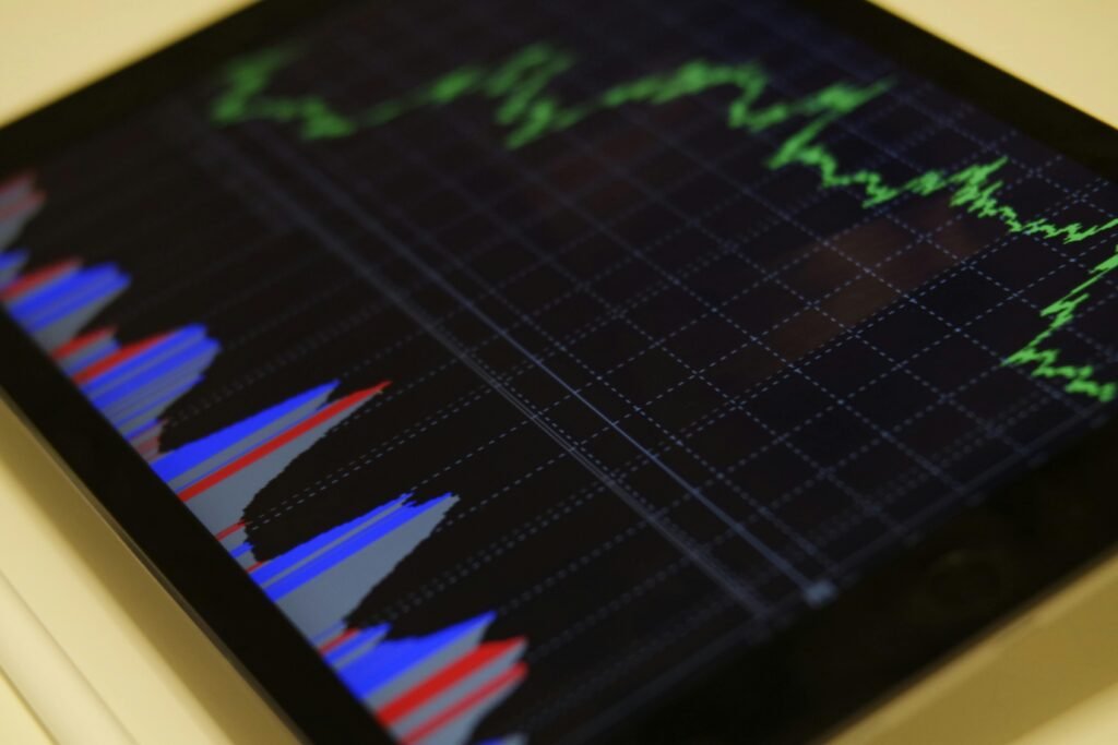 Tela de tablet exibindo gráfico de mercado financeiro com linhas verdes e barras coloridas, representando diferentes tipos de investimentos.
