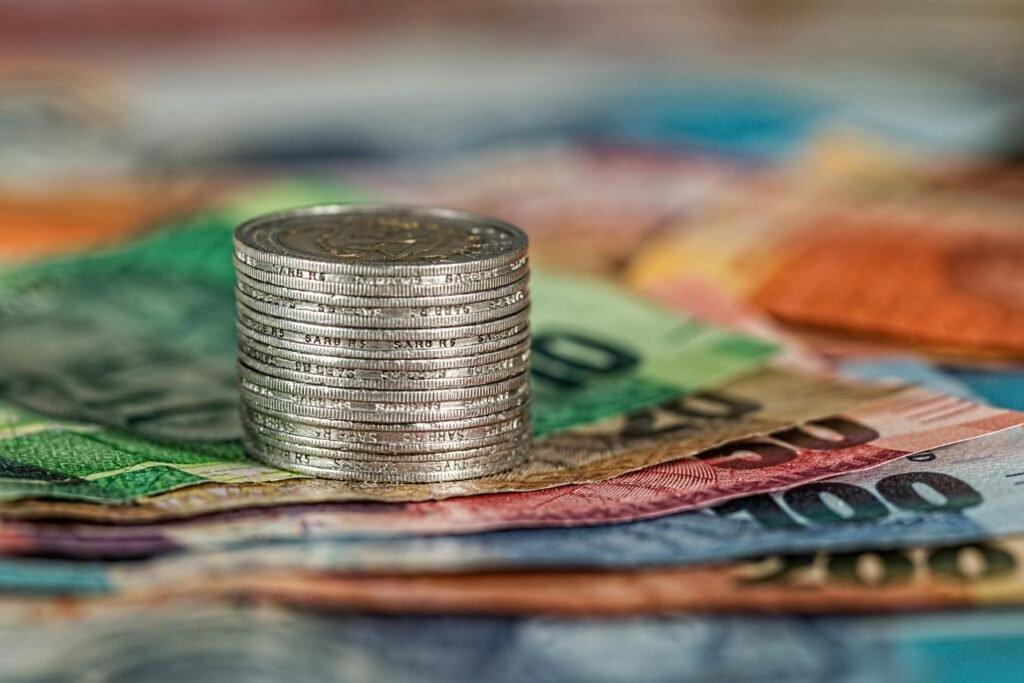 Pilha de moedas sobre notas de dinheiro, ilustrando o capital para começar a investir.