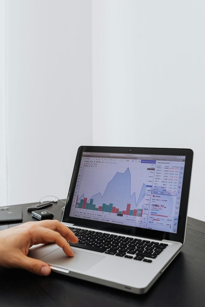 Uma pessoa analisando dados financeiros em um laptop com gráficos exibidos na tela.