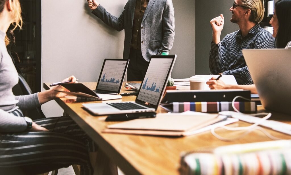 Equipe de investidores e analistas em reunião, discutindo gráficos de desempenho de ações em laptops, representando a análise e estratégia de investimento em Blue Chips no mercado brasileiro.
